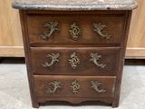 a wooden chest of drawers with a marble top and brass handles