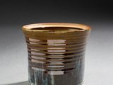 une tasse marron posée sur une table, sur fond noir