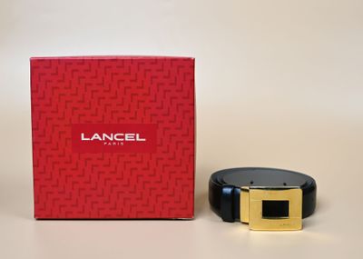 une boîte rouge avec une ceinture noire à côté et une boîte rouge avec une boucle dorée