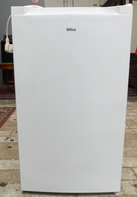 un réfrigérateur blanc posé à même le sol dans une pièce
