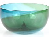 un bol en verre bleu et vert posé sur une surface blanche