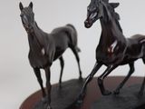 two statues of horses running on a wooden base