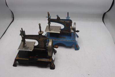 deux vieilles machines à coudre posées sur une surface blanche