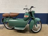 a green motorcycle parked in front of a blue and white wall