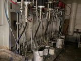 several buckets of milk are lined up in a row in a barn