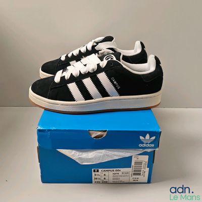 une paire de baskets noires et blanches posée sur une boîte