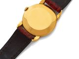 a close up of a watch on a white surface with a brown strap