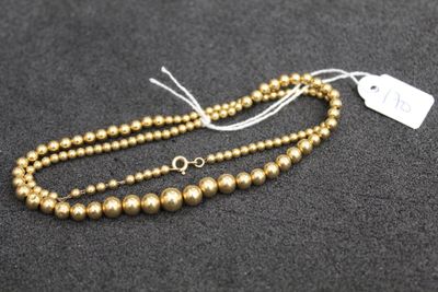 a gold beaded necklace on a black surface