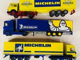 trois camions miniatures alignés sur une surface blanche