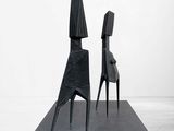two black sculptures are sitting on top of a black platform