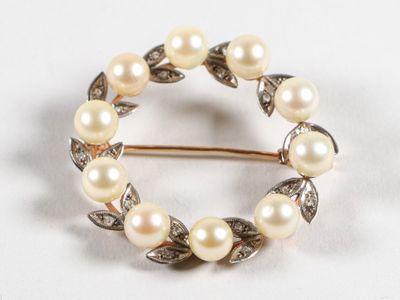 une image représentant une broche ornée de perles et de feuilles sur fond blanc