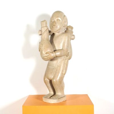 statue d'un homme tenant un oiseau, posée sur un socle jaune