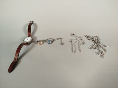 une montre et un bracelet posés sur une surface blanche