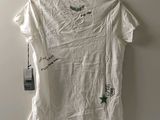 a white t - shirt with green writing on it hanging on a hanger