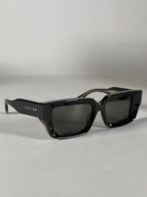 une paire de lunettes de soleil noires posée sur une surface blanche