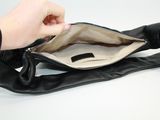 someone is holding a black purse with a zipper on the inside of it