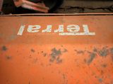 a rusted orange truck with a tire on the back