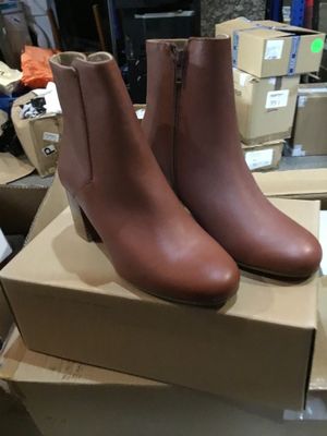 une paire de bottines en cuir marron posée sur une boîte en carton