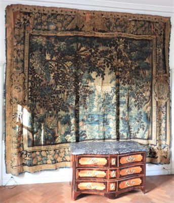 une grande tapisserie accrochée au mur, à côté d'une commode