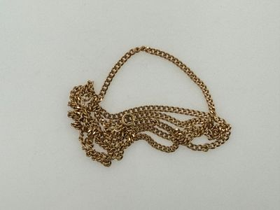 a close up of a gold necklace with a chain on a white surface