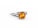 a close up of a ring with an orange stone surrounded by diamonds