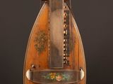 un vieil instrument de musique au corps en bois, posé sur une table en bois