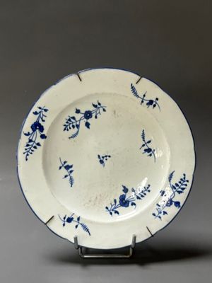 a blue and white plate on a stand on a gray surface
