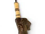an elephant ' s head with a wooden stick sticking out of it ' s trunk