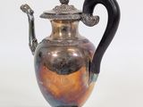 a silver vase with a black handle on a white background