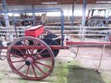 un chariot rouge avec un siège rouge, posé dans une grange