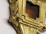 a gold clock hanging on the wall with a white background