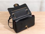 a small black purse sitting on top of a wooden table