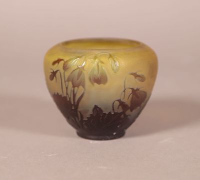 a yellow vase with flowers on it on a white surface