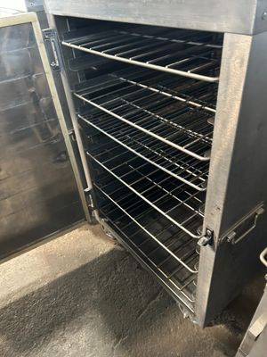 un grand four métallique contenant de nombreuses grilles remplies d'aliments