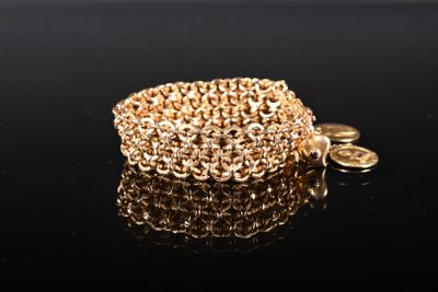 un gros plan d'un bracelet en or orné d'une pièce de monnaie, posé sur une surface noire