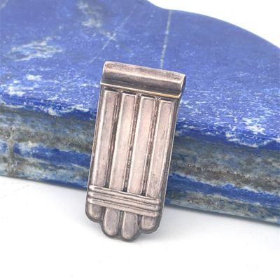 une épingle plaquée argent ornée de barrettes, posée sur une pierre bleue