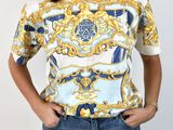 the woman is wearing a white shirt with a blue and gold pattern