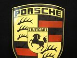 un gros plan sur l'emblème Porsche sur fond noir