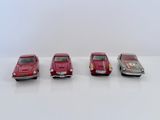 quatre petites voitures sont alignées sur une surface blanche