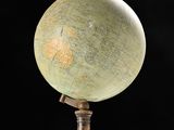 an old globe on a wooden stand against a black background