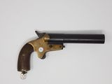 un vieux revolver avec une poignée en bois sur une surface blanche