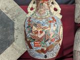 a vase with a painting on it sitting on a red cloth