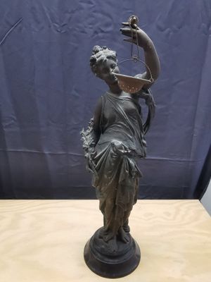 bronze statue of a woman holding a bird on a wooden table