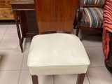 a chair and a stool in a room with a lot of furniture in the background