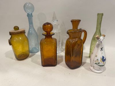 cinq vases en verre de couleurs différentes posés sur une surface blanche