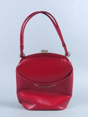 un sac à main rouge muni d'une poignée en métal sur fond blanc