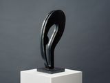 a black and white sculpture on a pedestal against a gray background