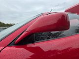 a close up of a red car with rain on the windshield