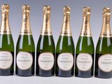 six bottles of champagne lined up in a row on a table