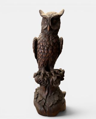 an image of a statue of an owl sitting on a tree stump